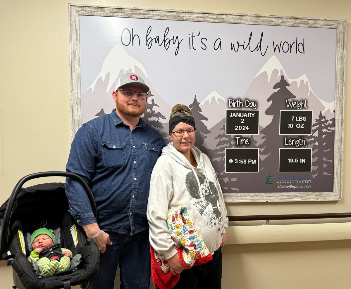 Allie standing next to Anthony who is holding a car carrier with baby Timothy in it